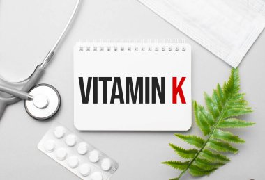 Not defteri, steteskop ve yeşil bitki üzerindeki K vitamini.