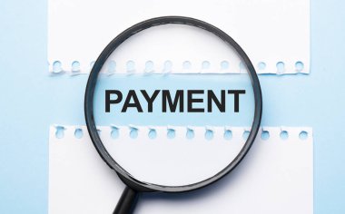 Mavi masadaki iki kağıt çarşaf arasında imzalı bir büyüteç..