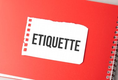 Kırmızı not defterindeki yırtık kağıt üzerinde ETIQUETTE kelimesi,.