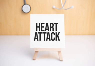 Küçük tahta üzerinde kalp krizi tabelası. Sehpada steteskopla dinleniyor.