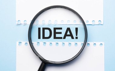 Mavi masadaki iki kağıt çarşaf arasında işaret fikriyle büyüteç..