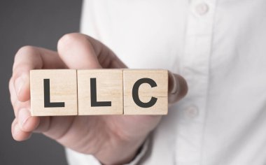 İş adamı el ele tutuşmuş, ahşap küp ve LlC metni. Mali, pazarlama ve iş kavramları