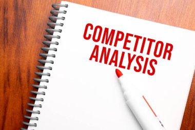 Not defterinde yazılı metin COMPETITOR ANALYSIS, yukarıdan ofis ahşap tablosu, blog başlığı veya başlık resmi için konsept resmi. Yıllanmış vintage rengi görünümü.