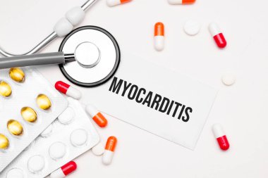 Stetoskop, ilaç ve not defteri. Masasında miyokardit kelimesi var..