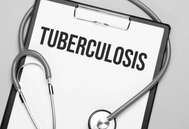 The words Tuberculosis is written on white paper on a grey background near a stethoscope. Medical concept