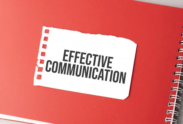 The word effective communication on torn paper on red notepad,.