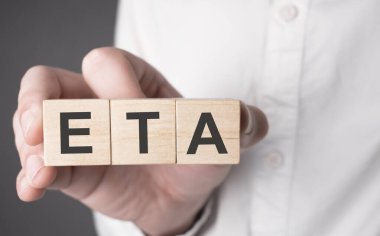 Business man hand holding wooden cube with eta text. Financial, marketing and business concepts