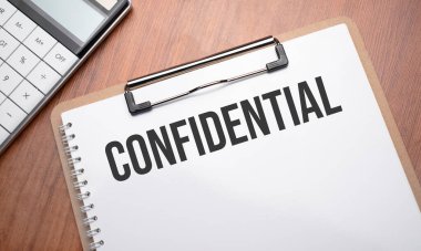 Tahta arkaplan, ataç, kalem ve hesap makinesi ile gizli metin içeren not defteri