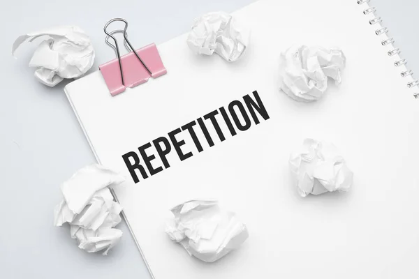 REPETITION. Blank sheet of paper, red paper clip, word Ideas and crumpled paper wads