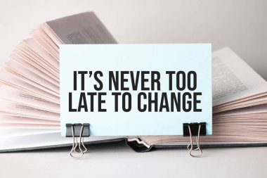 Üzerinde metin olan beyaz bir kart, kitapların arka planında duran kağıtlar için bir şarjör üzerinde durmak için asla geç değildir. Odaklanmayın