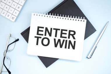 Enter to Win metni yazılıyor. Gri arkaplanda hesap makinesi, kalem, plan, gözlük ve siyah klasör