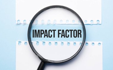 Mavi masadaki iki kağıt tabaka arasında IMPACT FACTOR imzalı büyüteç hoparlörü.