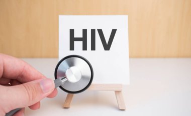 Doktor steteskop ve sehpayı HIV ile tutuyor.