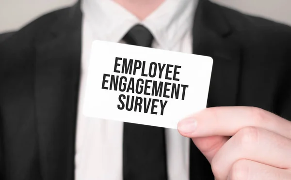 Businessman holding a card with text Employee Engagement Survey