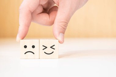 Kapalı müşteri eli seç. Gülen surat ve tahta küpte bulanık surat simgesi, servis derecesi, memnuniyet konsepti..