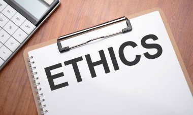 Tahta arkaplan, ataç, kalem ve hesap makinesi ile metin etiği içeren not defteri