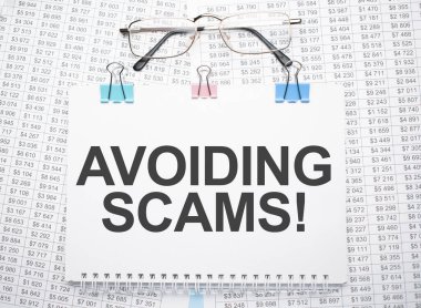 Kağıt üzerine kalem ve gözlük ile yazılmış dolandırıcılıktan kaçınma