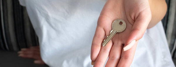 Female hand holding house key,real estate agent.