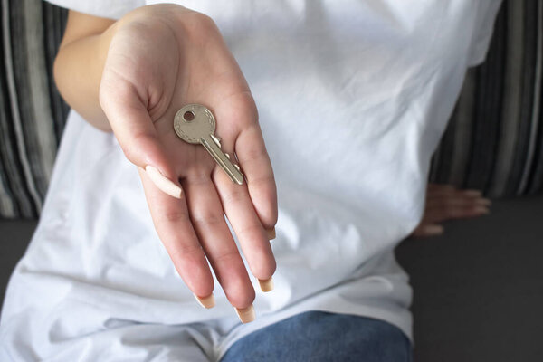 Female hand holding house key,real estate agent.