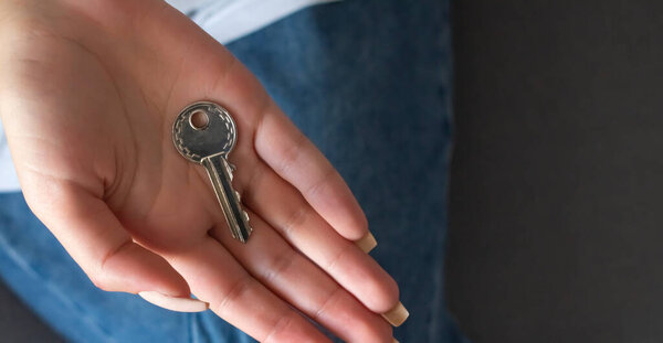 Female hand holding key house shaped keychain.