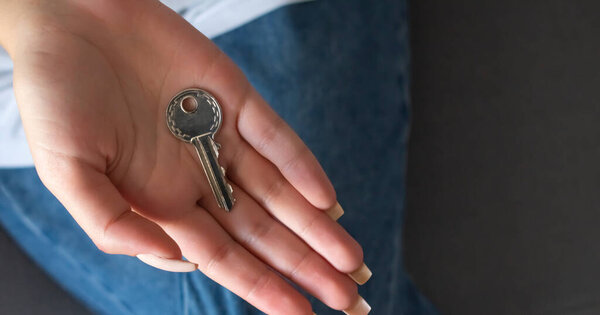 Hand holding house key of a property as a concept for house purchase and ownership