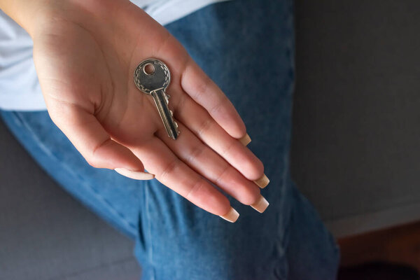 Female hand holding house key,real estate agent.