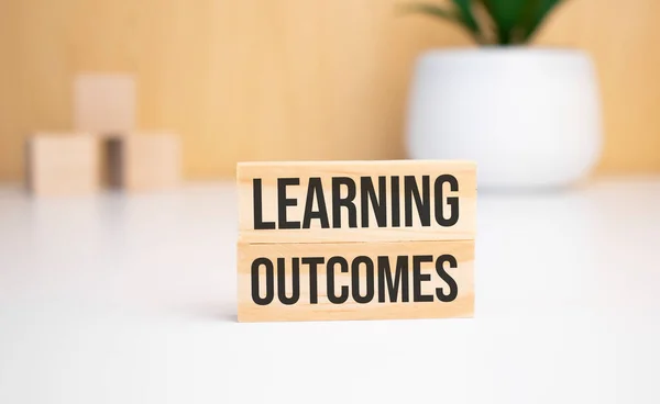 Hafif bir arka planda, tahta küpler ve metin öğrenme sonuçları olan tahta bir blok. Yukarıdan görüntüle