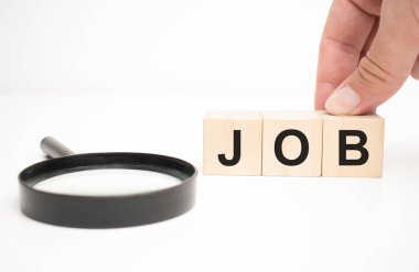 Çalışma metni ahşap küp bloklar ve masa arkasında el ele büyüteç.