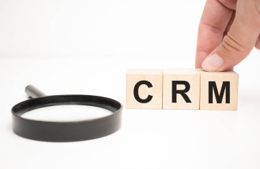crm metin ahşap küp bloklar ve masa arka planında el ele büyüteç.