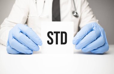 Doktorun elinde steteskopla STD mesajı olan beyaz etiket.