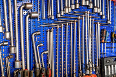 Kullanılmış mekanik aletler, kombinasyon anahtarlarından tornavidalara ve soket anahtarlarına kadar. Hepsi mavi panellerde asılı. Sanat ve zanaat için mükemmel bir atış..