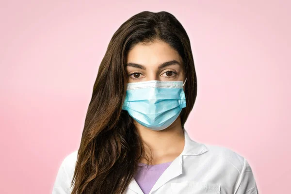 A scientific researcher in a surgical gown and mask. In a pink background. Perfect shot for pandemic, research, vaccine and security.