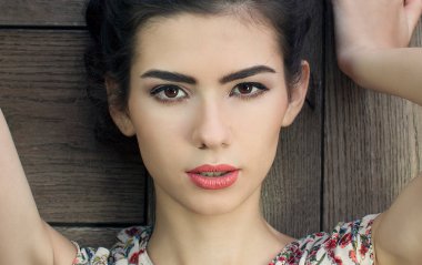 Tahta duvarda poz veren güzel esmer kadın.