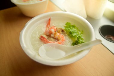 Köpük bir fincanda karides lapası, ahşap bir masaya konur ve sabah ışığı ile, üst manzara.