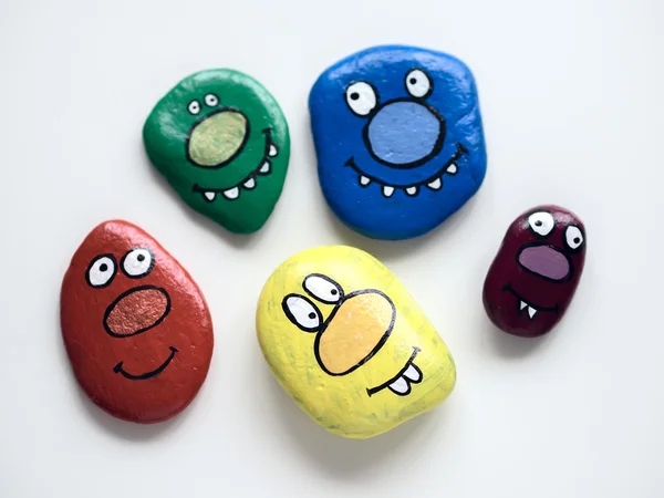 Five smiling faces of monsters. Painted acrylic pebbles. — Stock Photo, Image