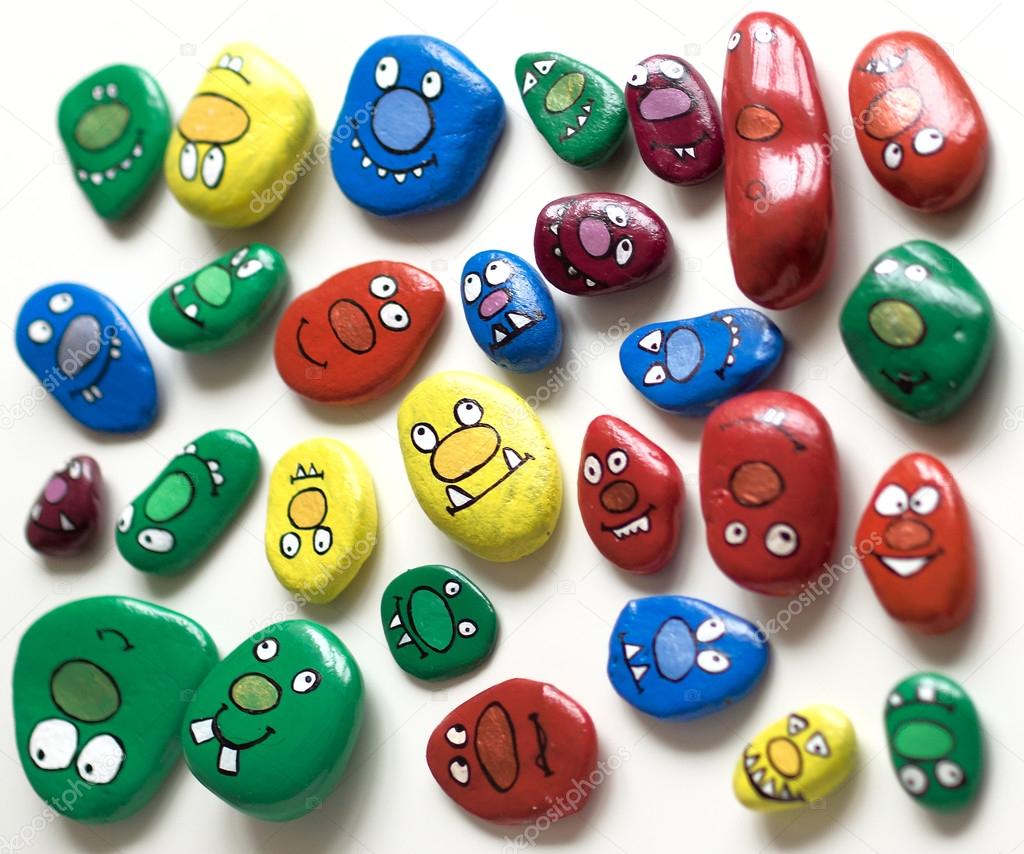 Set of smiling faces of monsters. Painted acrylic pebbles.