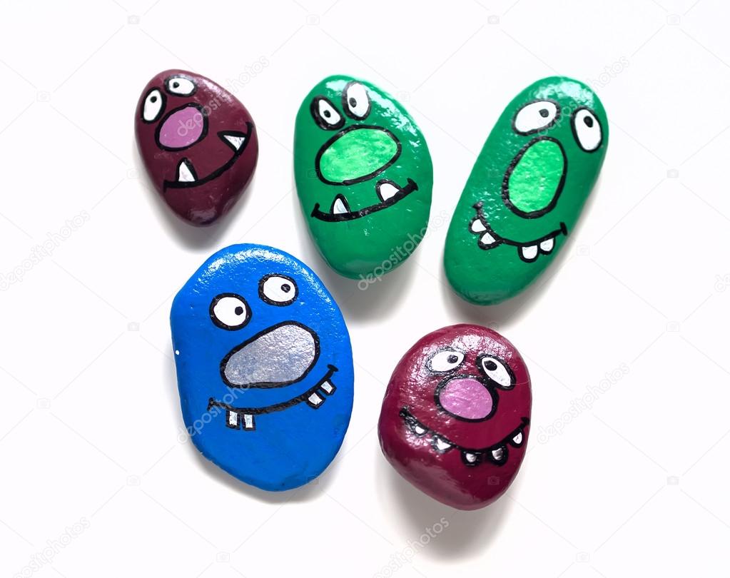 Five smiling faces of monsters. Painted acrylic pebbles.