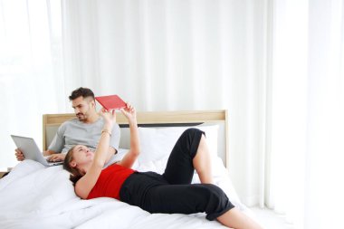 Genç beyaz çift yatak odasında online alışveriş yapmak için sosyal medyada dizüstü bilgisayar ve tabletle rahatlamaya bayılıyor. Evli aile yaşam tarzı teknolojisi Tatil kavramı.