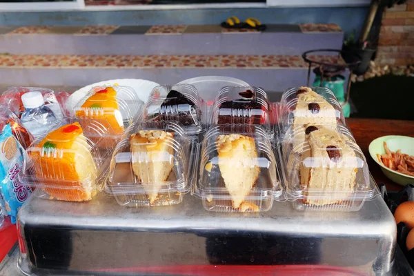 カンチャナブリ2017年9月10日 タイの田舎のストリートマーケットで甘いお店で販売されているテーブルの上のプラスチック製の箱に手作りケーキのピース — ストック写真