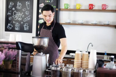 Asyalı barista genç adam gülümsüyor ve kafede kahve yapmaya hazırlanıyor. İş adamı konseptine başla.