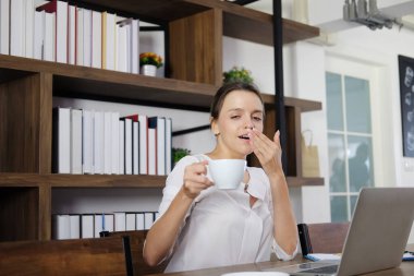 Gülümseyen beyaz kadın sabahın köründe kafede güneşin doğuşuyla bir fincan sıcak kahveyle mutlu oluyor. Ofisteki kafede tabletle dinleniyor. İş kadını yaşam tarzı ve teknoloji konsepti