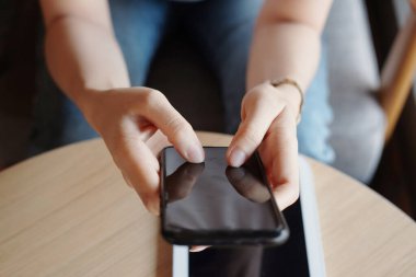 Kapalı el, internet ve sosyal medyayla online alışveriş için akıllı telefonu tutuyor ve daktilo ediyor. Asyalı kadın ofiste tabletle çalışıyor. Evden çalışmak için iş ve teknoloji.