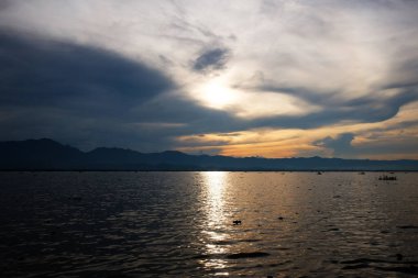 Güzel Siluetin ve gün batımının istikameti su yüzeyine yansıyan ışık ve nehirde parlayan dalgalar.