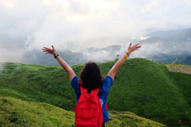 Asyalı kadın, vadideki ormanın sisli ve sisli bölgelerinde parlayan altın gündoğumu ve günbatımı cenneti için ellerini açık tutuyor. Hava görüntüsü Tayland 'daki tropikal yağmur ormanları.