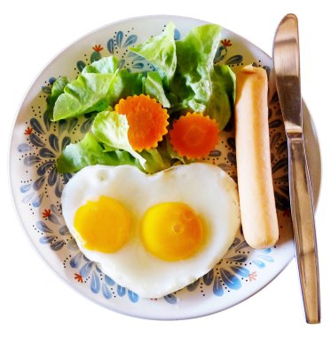 Fresh heart shaped fried eggs with organic vegetable salad and hot dog in white dish breakfast isolated on white background with clipping path