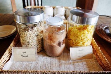 Various uncooked cereals with muesli and corn flake in glass jar on table