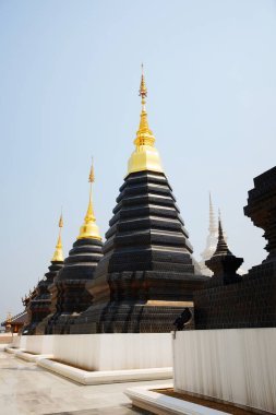 Tayland 'ın Chiang Mai bölgesindeki Wat Den Sali Mueang Kaen tapınağında Budizm' in altın pagoda sembolleriyle kadim siyah.