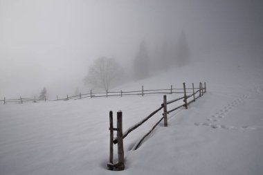 Dağların tepesindeki eski ahır kışın bulutların arasında. Yoğun sis. Seçici odaklanma. Bulanık arkaplan.