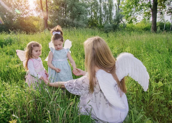 優しい魔術師と小さな女の子は 太陽の光の下で緑の芝生の上に翼を持ち去る 選択的フォーカス ぼやけた背景 — ストック写真