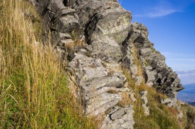 Mavi gökyüzünün arka planında dağ otları olan uçurumlar..